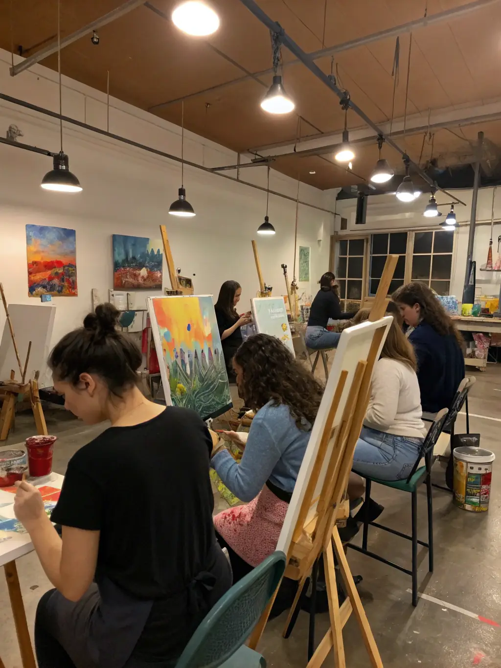 An image of a lively art workshop with participants painting and engaging with instructors in a bright studio.